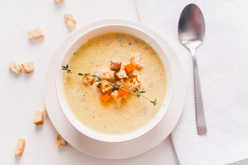 A healthy, dietary dish for lunch. Cream of vegetable soup with croutons and thyme. in a plate on a white table, view from above. selected focus.