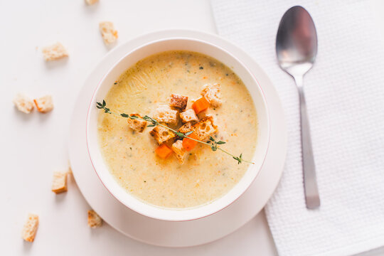 A healthy, dietary dish for lunch. Cream of vegetable soup with croutons and thyme. in a plate on a white table, view from above. selected focus.