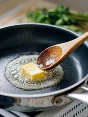 Butter melting in hot pan with wooden spoon, steam rising, herbs visible in background