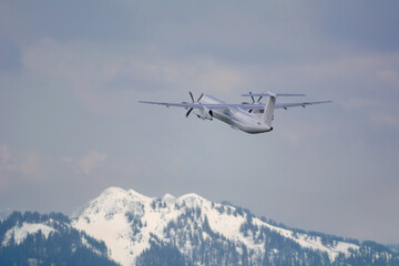 Fototapeta na wymiar 白い雲と青空、雪山のアルプス山脈を背景に飛行機が飛ぶ