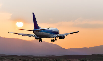 夕焼けの空から太陽、山間部の空を飛ぶ飛行機