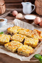 Slice of fresh homemade cottage cheese cake and yeast dough, covered with crumble on a table