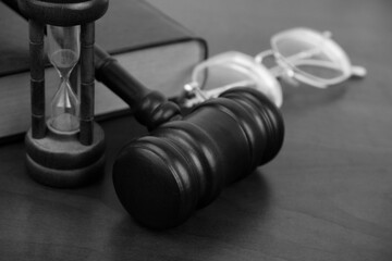 Judge gavel, hourglass, eyeglasses and book on wooden table. Legal proceeding time concept.