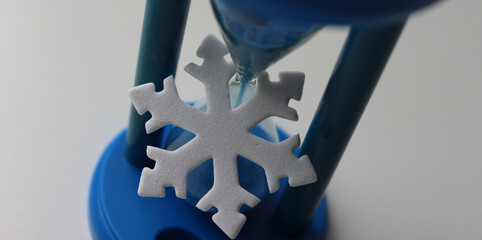 Symbol of Cold and Symbol Of Time. Blue Time Glass and White Snowflake Figurine Isolated on White....