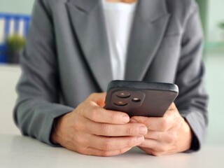 Female hands holding black smartphone and typing.