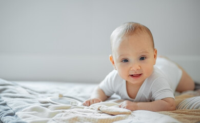 Fototapeta premium Portrait of cute small baby lying on tummy and looking to the camera. Newborn child.