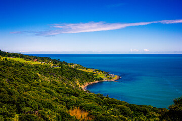 Panoramic view over high coast of Tasman Sea on an overcast summer day. High vantage point. Raglan, New Zealand