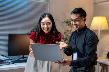 Asian business people celebrating success while looking at laptop screen