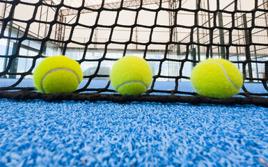  paddle tennis balls near the lines of a blue paddle tennis court, racket sports concept