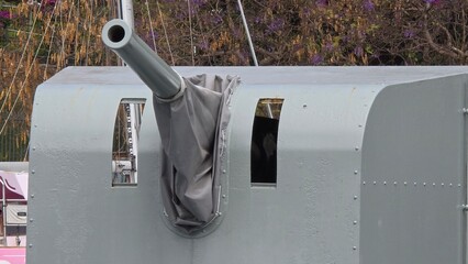 Grey WWII naval artillery gun cannon with protective metal canopy