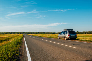 the car is parked on the side of the road at sunset in the evening