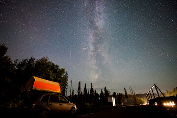 Fototapeta premium The Milky Way in the starry sky above a car with a tent