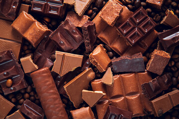 Background of broken pieces of dark and milk chocolate and coffee beans.