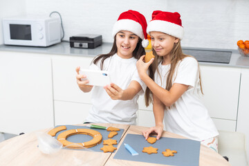  girls making Christmas cookies with cookie cutter. Child playing with dough. Christmas tradition. Helper in a kitchen. 