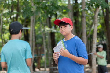 Asian schoolboys are studying high level of trees in school botanical garden by using inclinometer...