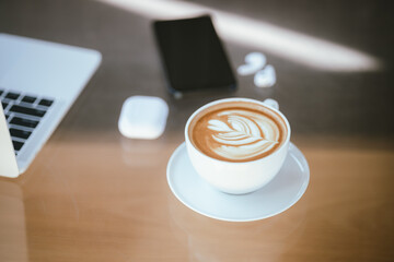 A cup of coffee is placed near a laptop on a table with space for copying documents, suggesting a break from work or a relaxing time at a cafe.