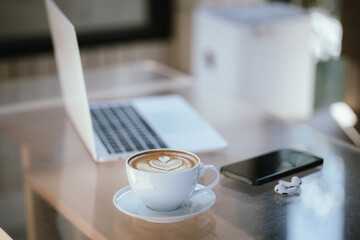 A cup of coffee is placed near a laptop on a table with space for copying documents, suggesting a break from work or a relaxing time at a cafe.