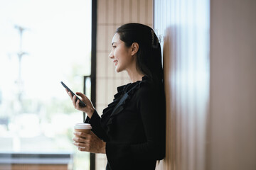 Happy and smiling Asian businesswoman with smartphone with success concept at work