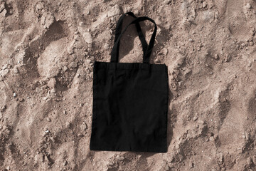 Black cotton or mesh bag on beach sand background. Zero waste, no plastic, eco friendly shopping,...