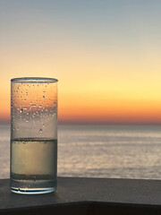 A glass of champagne sits on a terrace ledge, with a stunning backdrop of the ocean and distant mountains under a clear sky. The scene exudes luxury and relaxation.
