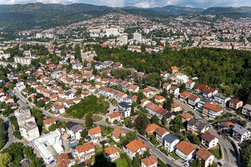 A scenic aerial view of a suburban neighborhood nestled within a lush green landscape and hills in the background. Showcases residential living in harmony with nature, suitable for real estate.