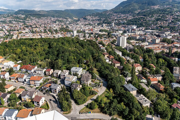 A scenic aerial view of a suburban neighborhood nestled within a lush green landscape and hills in the background. Showcases residential living in harmony with nature, suitable for real estate.