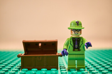 Obraz premium Closeup of Lego DC Comics The Riddler toy figurine villain standing next to a treasure.