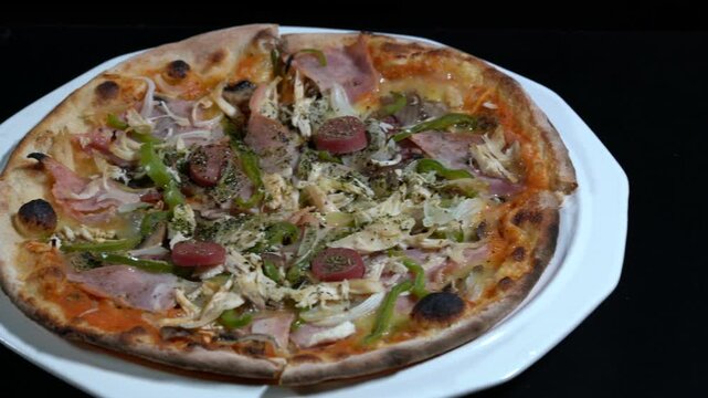 Delicious combo pizza sliding on a white plate against a striking black background, showcasing a mouthwatering meal