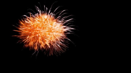 A bright orange firework explodes in the night sky, illuminating the dark with its dazzling display