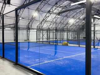 empty paddle tennis court with lights on in a covered shed with no players