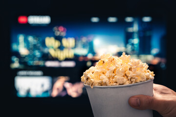 Tv streaming and popcorn. Watching movie from stream service in television. Film night and snack. Pop corn, couch and vod series. Home cinema in living room. On demand video content online.