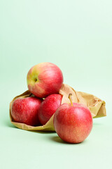 Red apples and in a kraft paper bag. Green background and copy space.