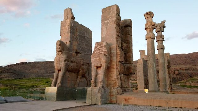 Camera panning across massive statues at persepolis, iran, showcases the stunning architecture during a vibrant sundown