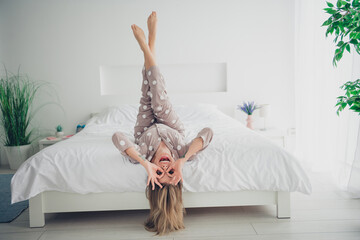 Young woman enjoying playful morning in cozy bedroom with feet up on the bed