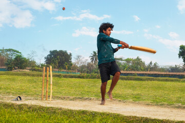 Rural boy playing cricket in village located in West bengal, India