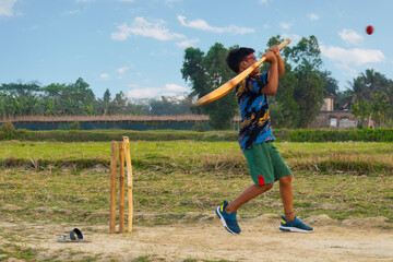 Rural Boys playing cricket on dirt pitch in village located in West bengal, India