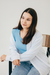Obraz premium A woman in a white shirt and jeans showing a stylish and understated look. The light background and natural pose give the shot a modern feel.