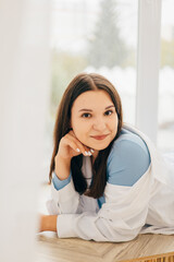 Obraz premium girl leaning against the wall, smiling, light portrait