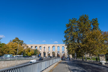 Obraz premium Traffic in Ataturk boulevard with view of Valens Aqueduct in background. Cloudy autumn view.