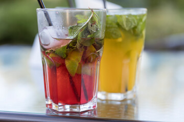 Two glasses of mixed drinks sit on a table