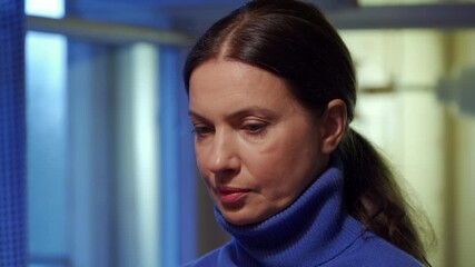 Adult 44 year old woman sitting in living room and having lively conversation. Woman with a worried, tense face is talking.