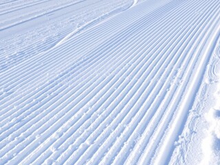 Fresh snow groomer tracks on a ski piste with perfectly manicured corduroy patterns, snowcat, piste