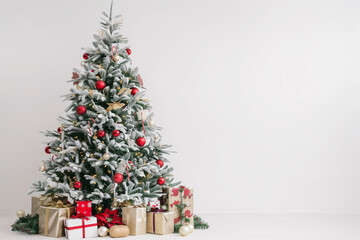 A Christmas tree with a variety of festive decorations and gifts underneath, photographed on a plain white background.