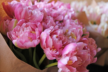 Double pink tulips in paper packaging for sale in a flower shop closeup.