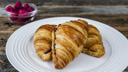 Three croissants with jam are on a white plate, ready to be eaten