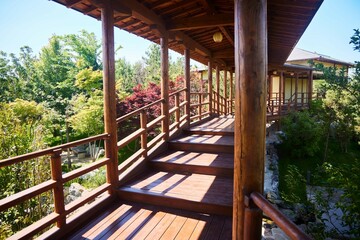 A wooden walkway with a view of the trees and the bridge. The walkway is connected by wooden posts and has a wooden railing