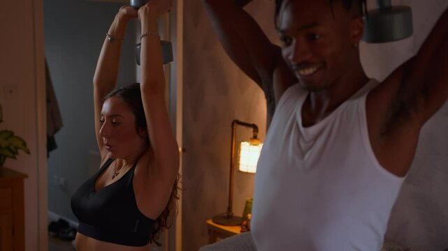 Athletic young couple exercising at home together weight lifting