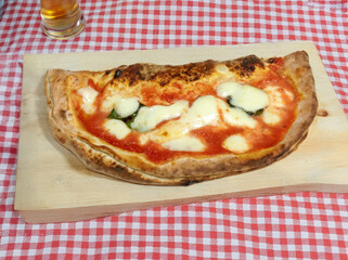 Delicious calzone margherita resting on wooden cutting board