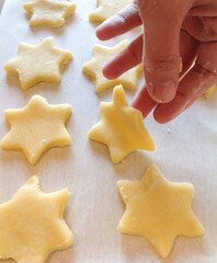 Pastry chef arranging star shaped cookies on baking sheet