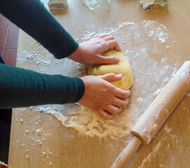 Baker kneading dough for christmas cookies on wooden table